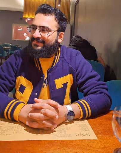 Man wearing a purple hockey jersey sitting at a wooden table.