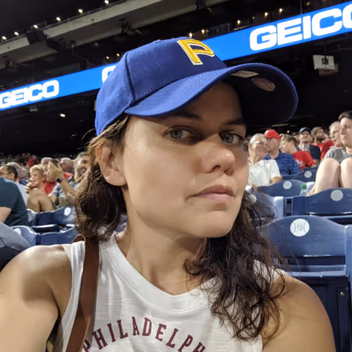 Woman wearing a baseball cap and tank top at a sports event