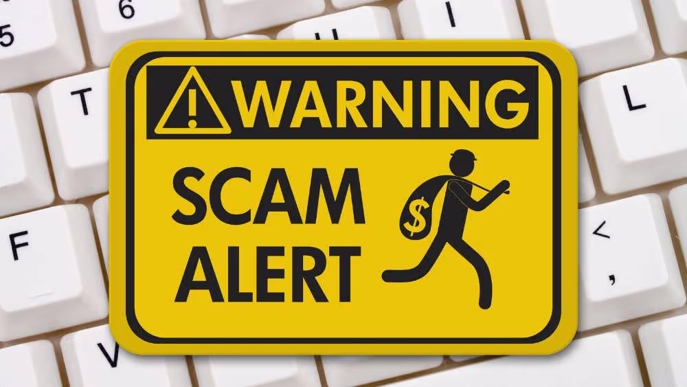 Yellow scam alert warning sign on a keyboard