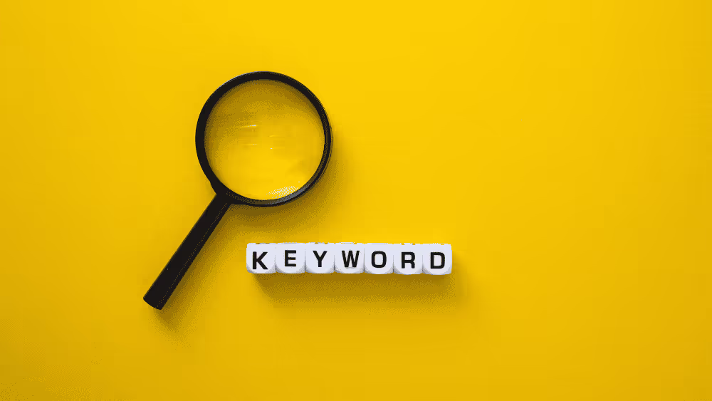 Magnifying glass above tiles spelling keyword on a yellow background