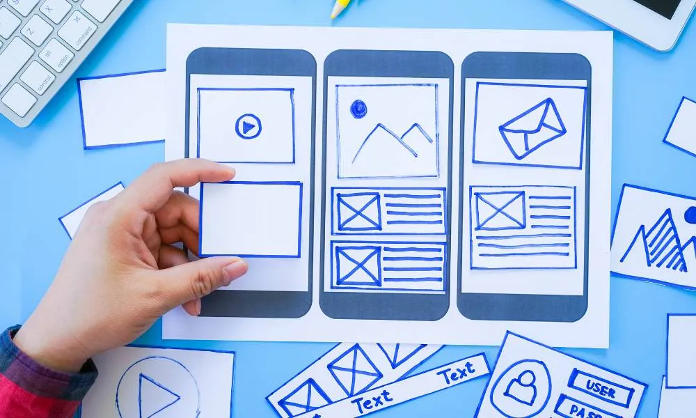 Paper mobile interface layouts arranged on a blue surface
