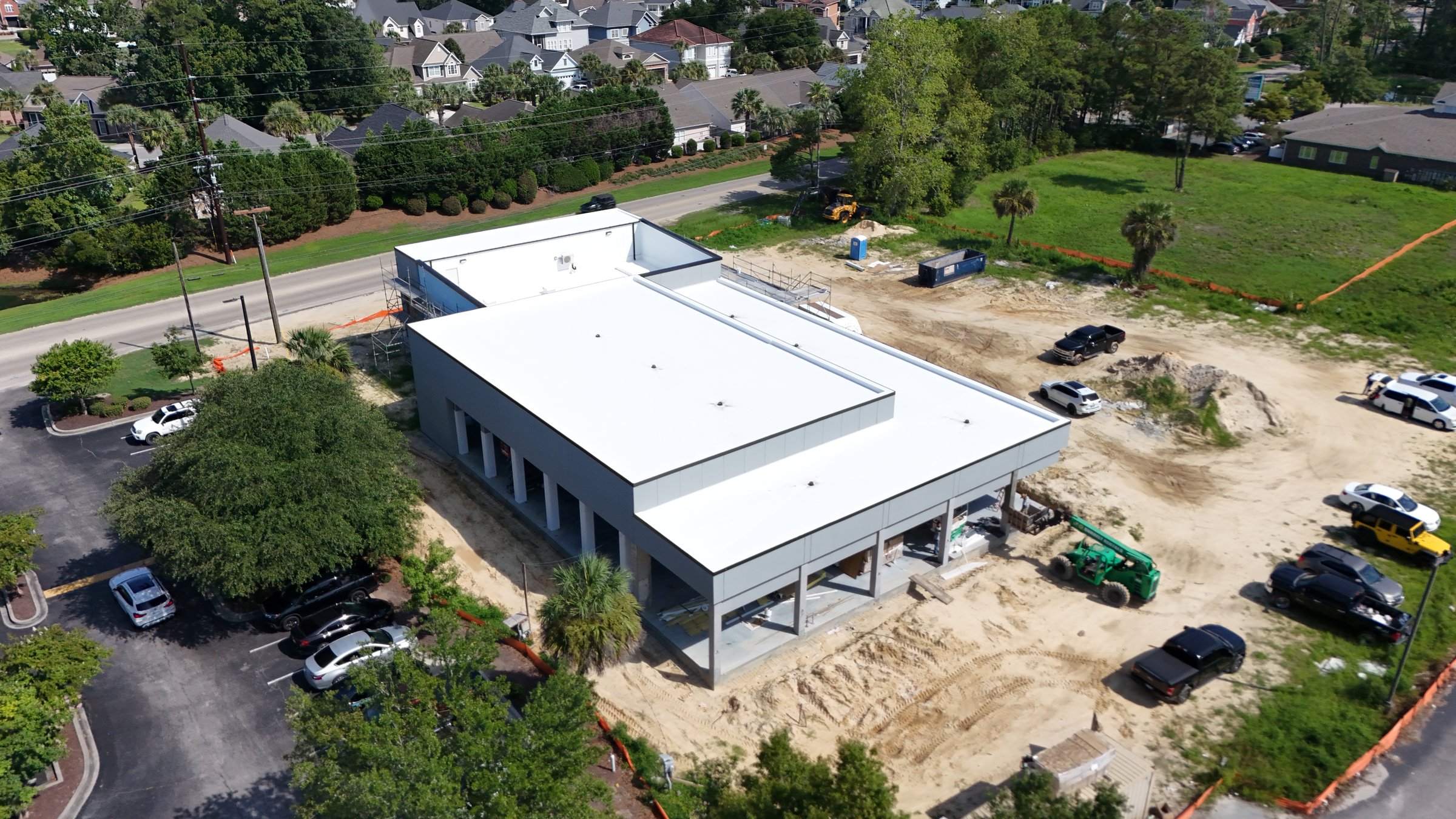 Aerial view of a commercial building under construction with a new white low-slope roof.