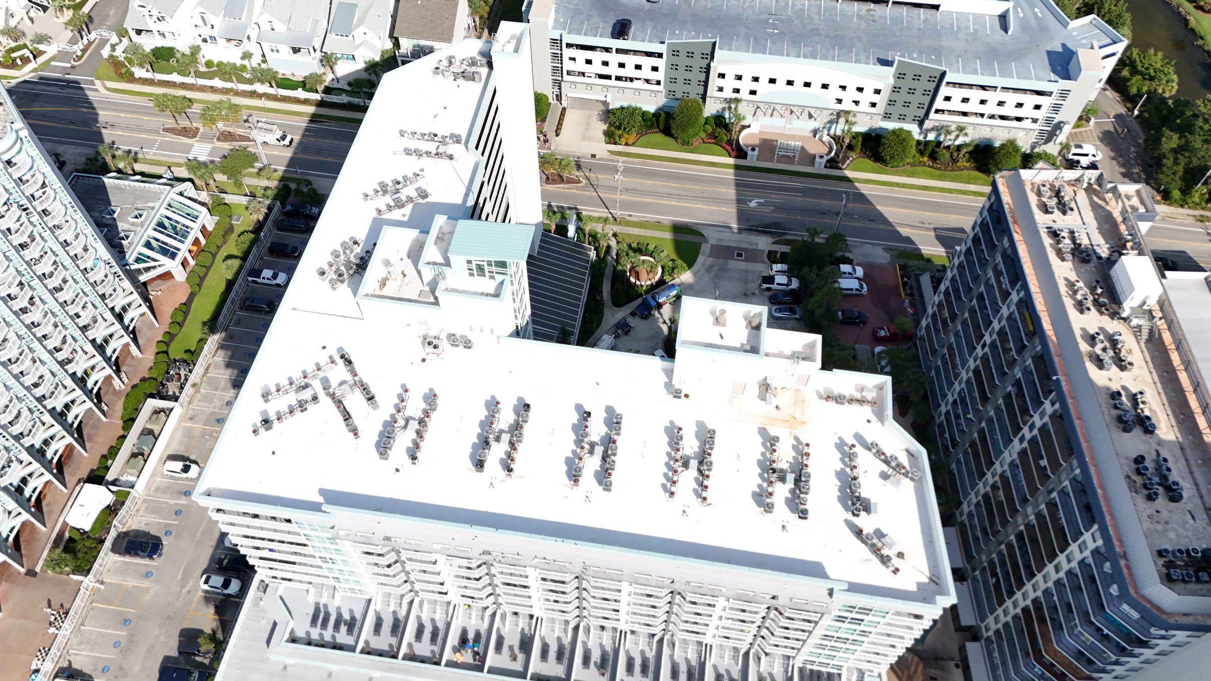 Aerial view of rows of HVAC units installed across a large white low-slope commercial roof.