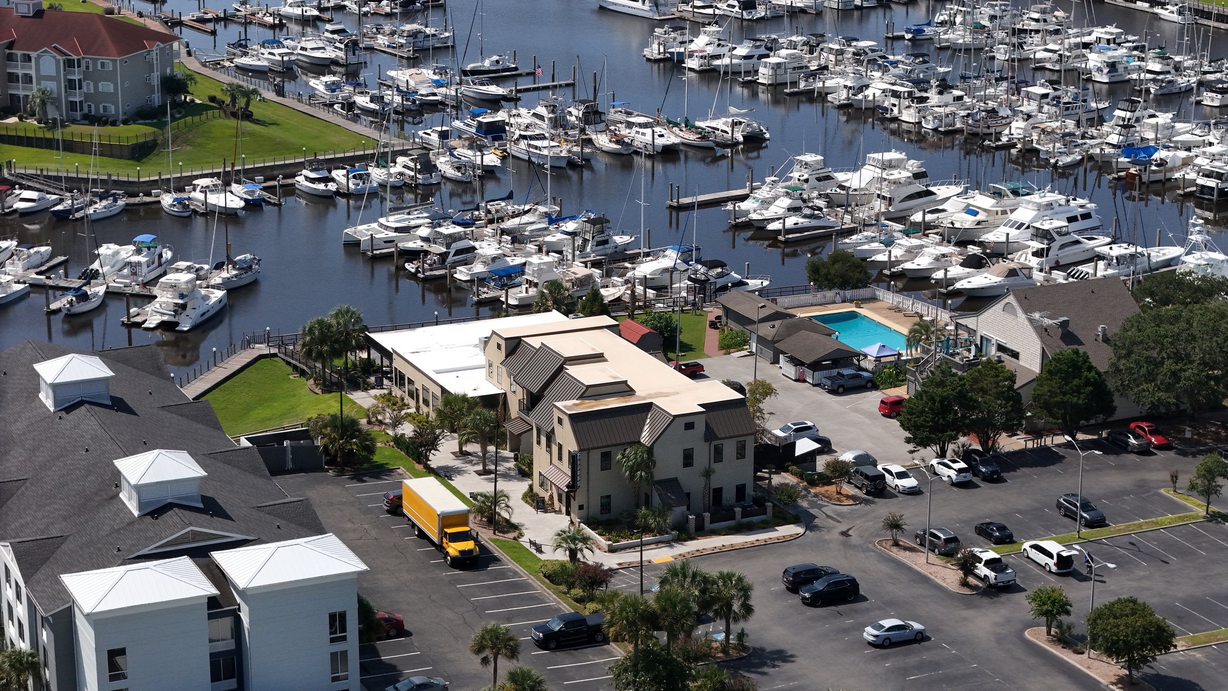 Aerial view of commercial buildings beside a marina full of boats.