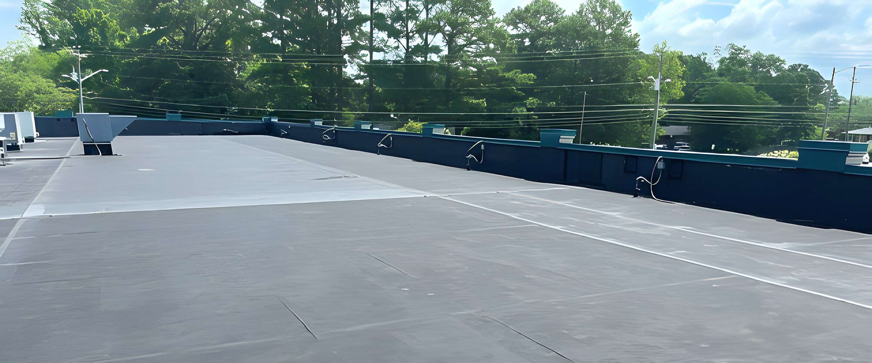 Flat EPDM membrane roof with sealed seams and edge drains on a commercial building.