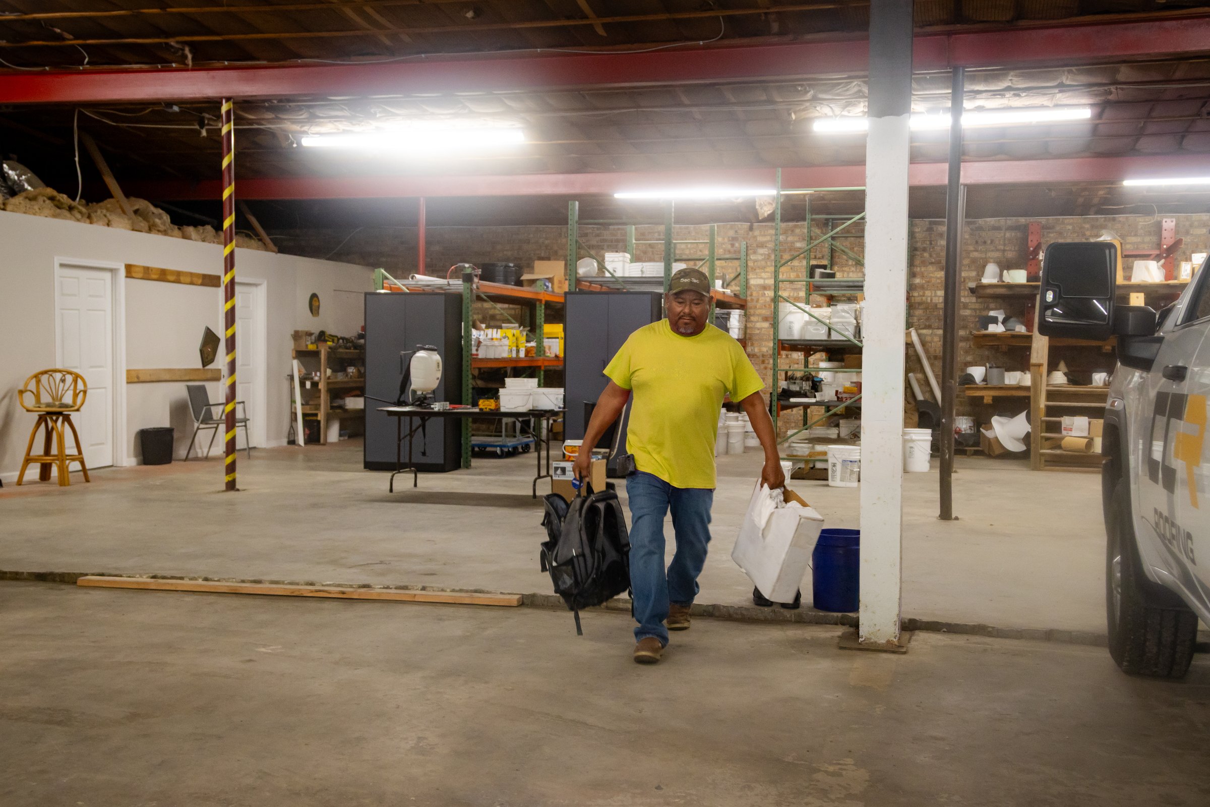 A Coastal Commercial Roofing worker carrying equipment through the company warehouse.