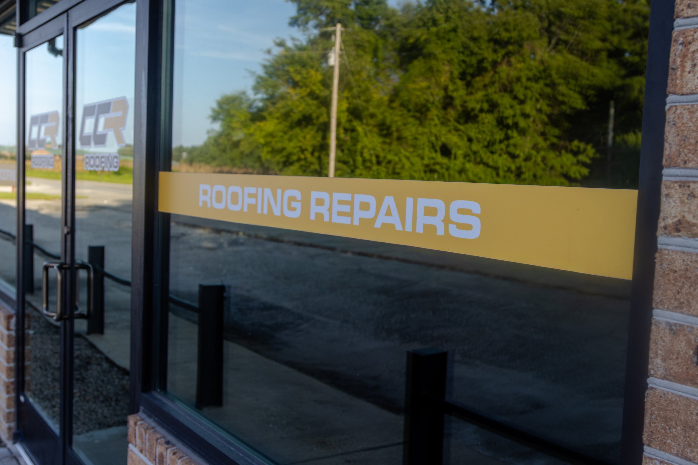 A Roofing Repairs window decal on the Coastal Commercial Roofing office.