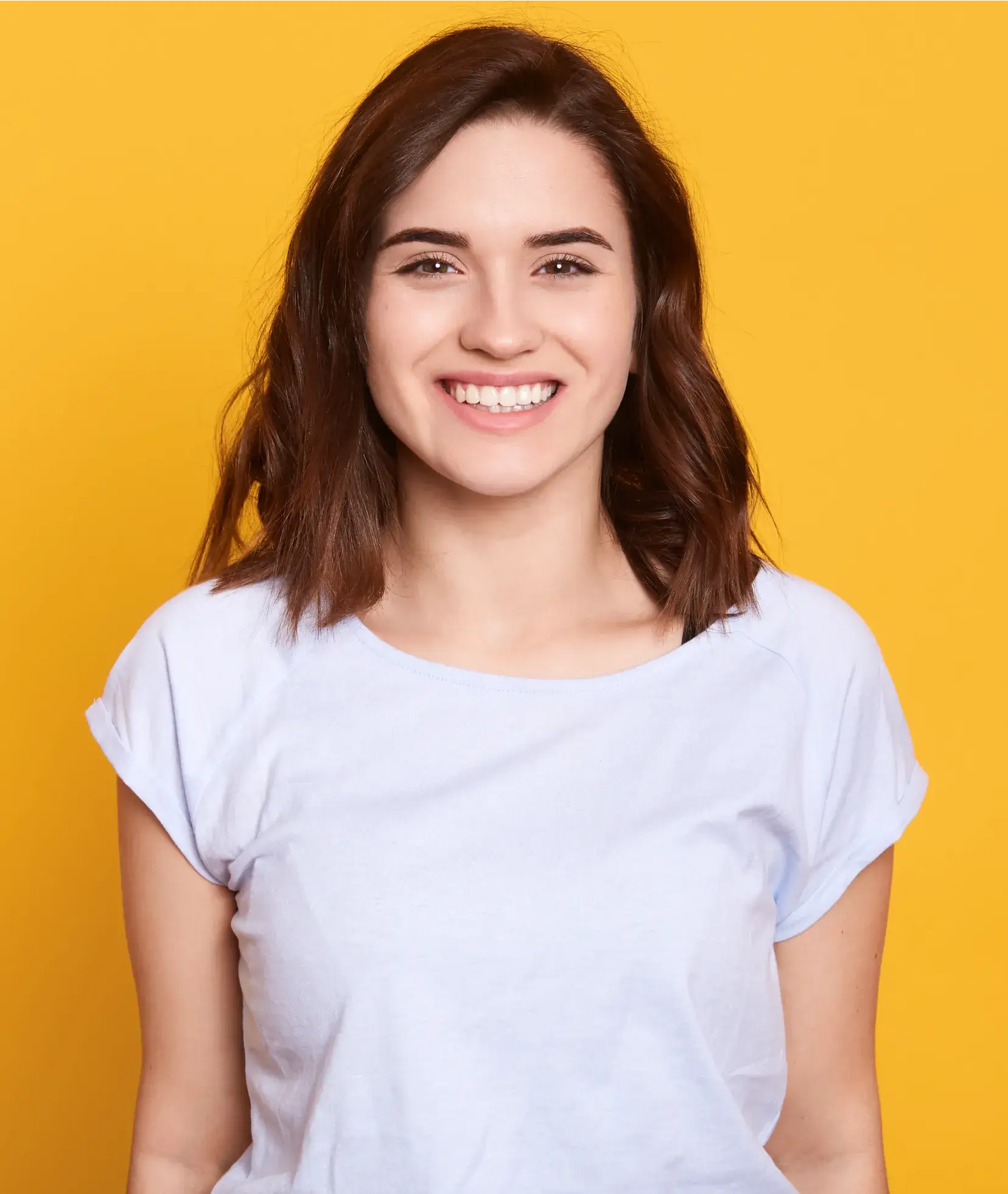 A smiling woman in a white t - shirt against a yellow background.