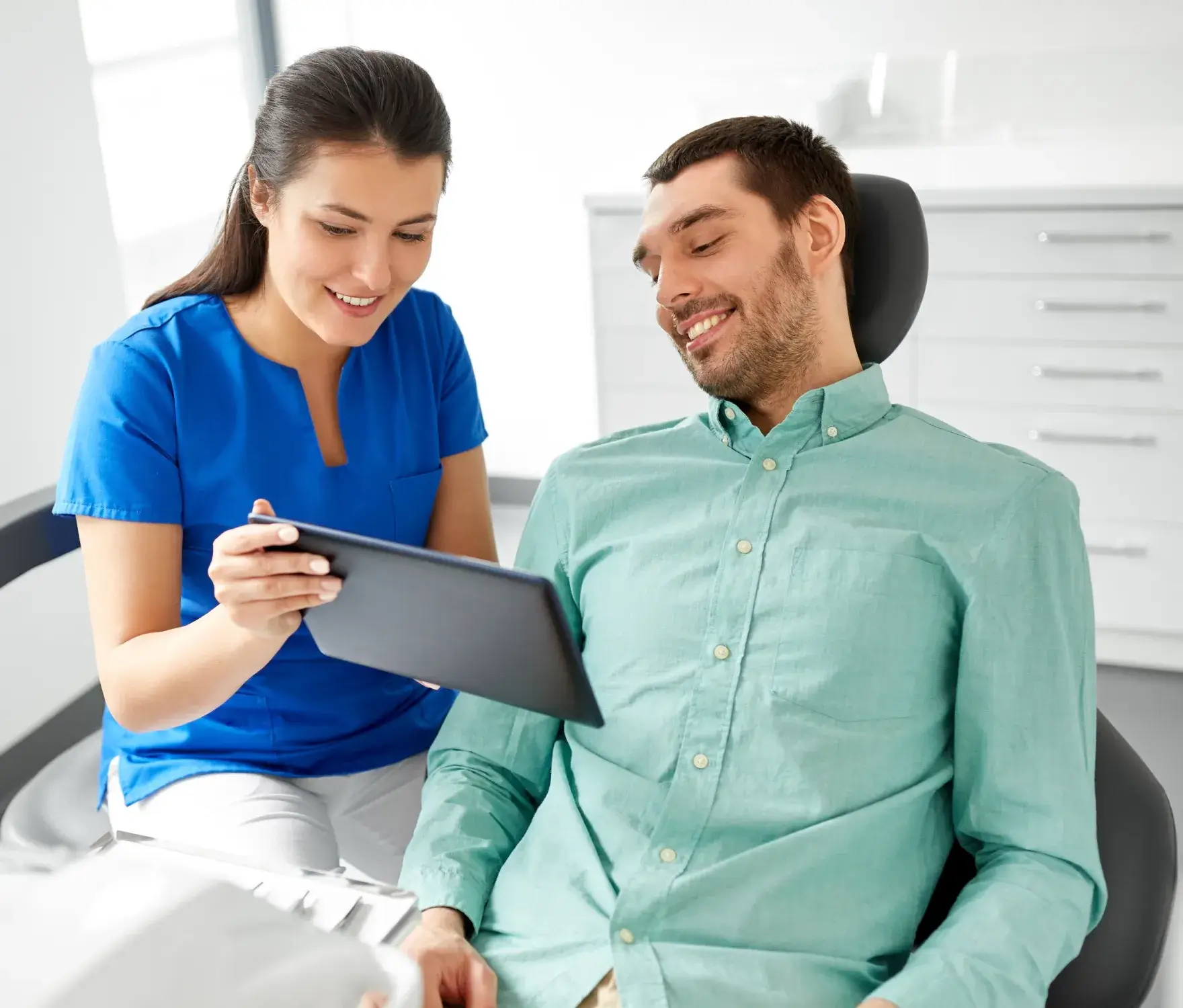 A dental professional shows a patient information on a tablet in a dental office.