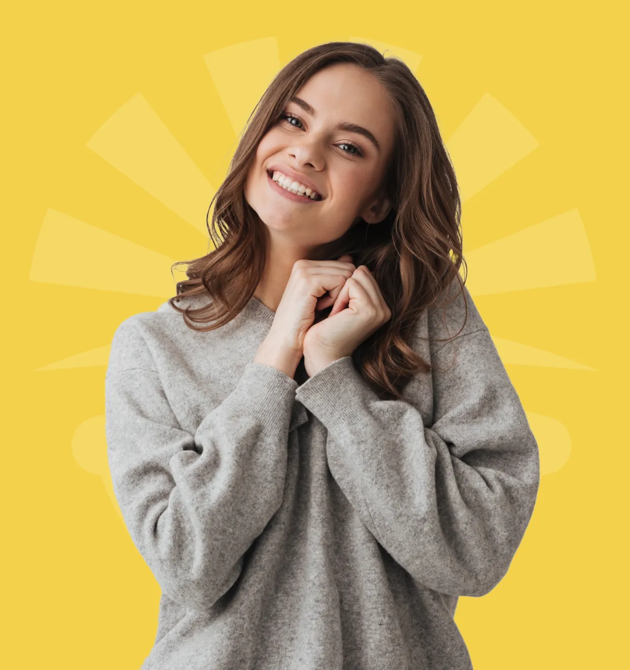A person in a gray sweater smiles brightly against a yellow background.