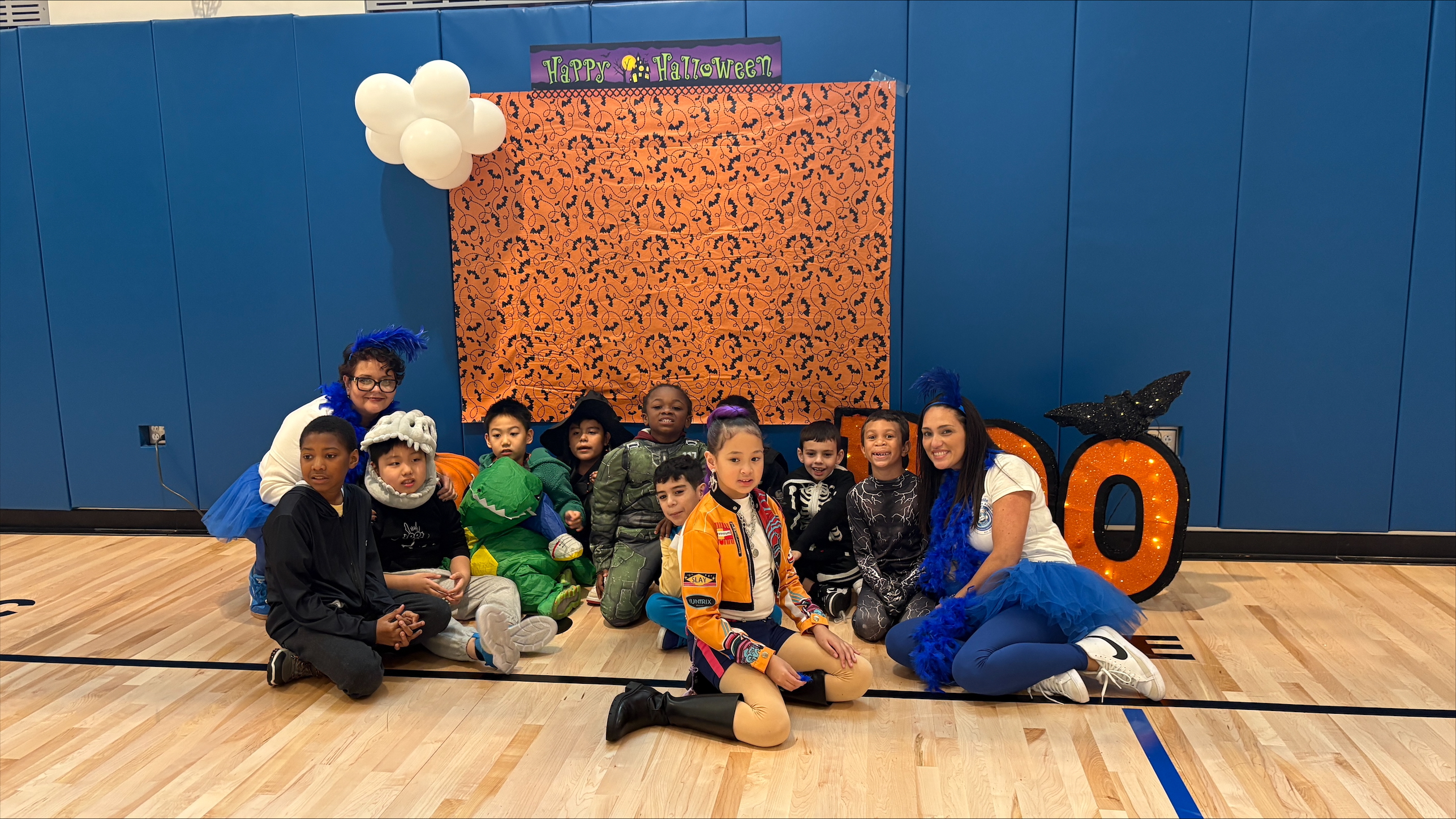 Students and teacher posing in Halloween costumes in school gymnasium
