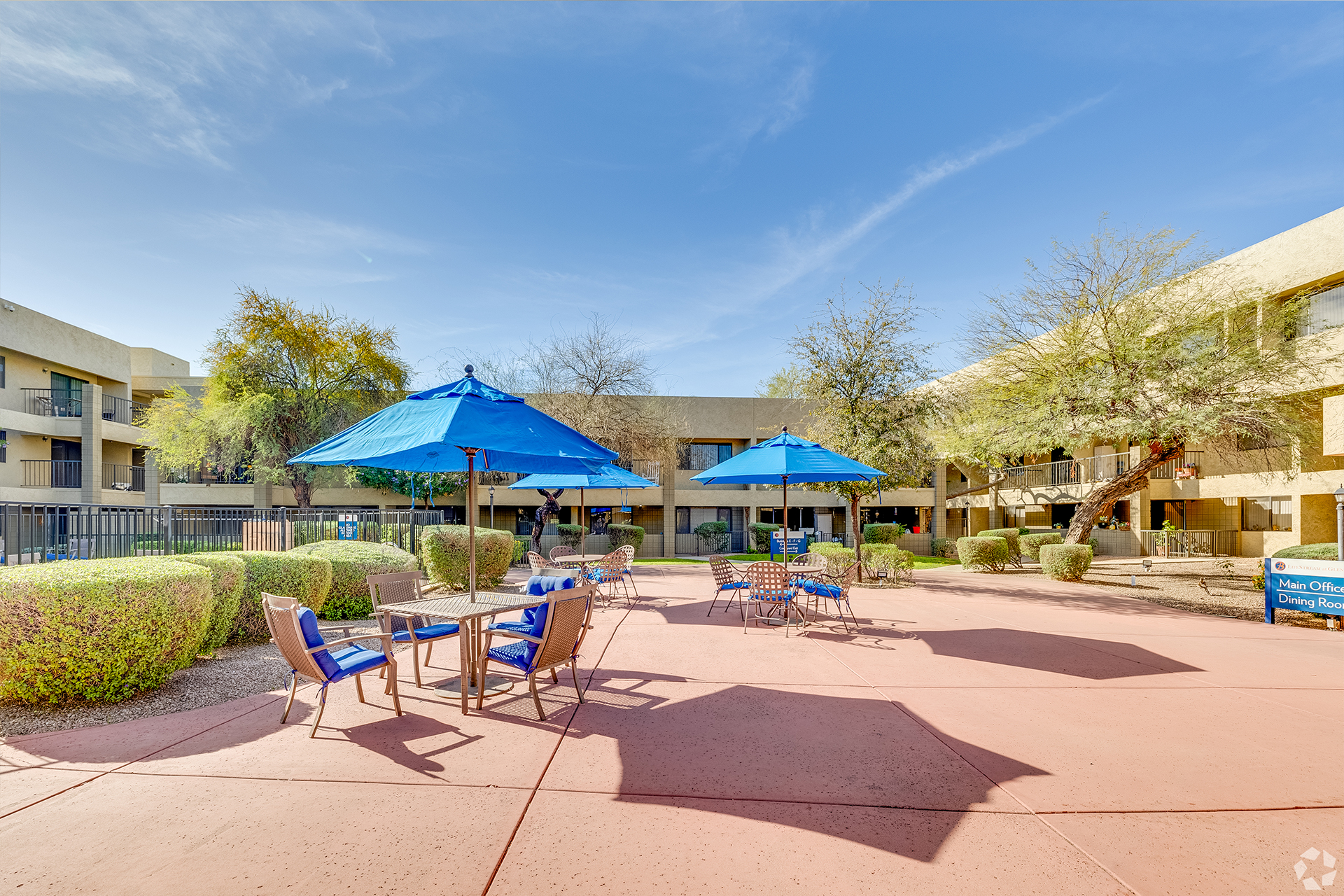 Courtyard tables with blue sun umbrellas — view 1 at LifeStream at Glendale.