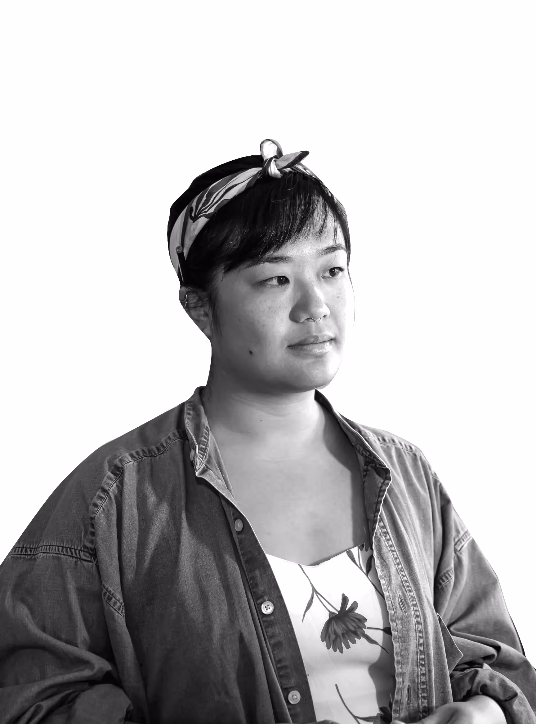 Portrait en noir et blanc d'une femme portant un bandana, une chemise en jean et une robe fleurie, regardant vers la droite.