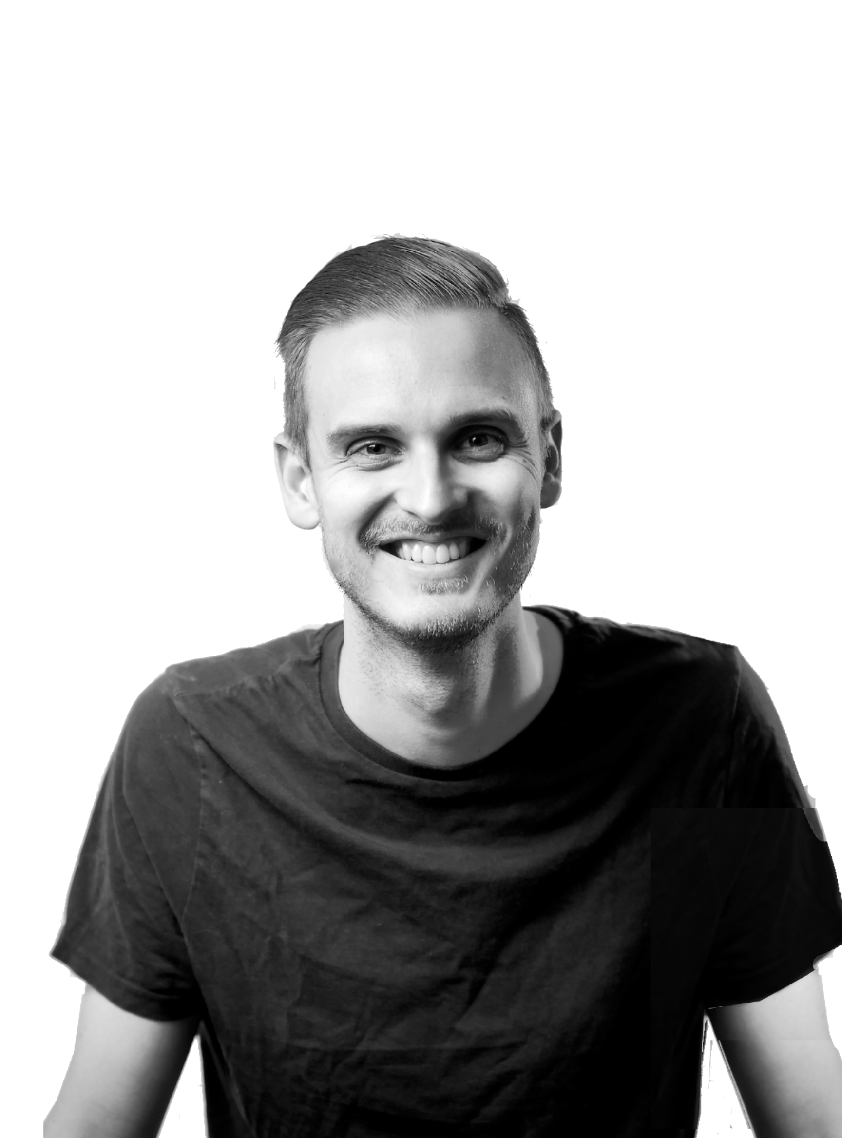 Homme souriant portant des lunettes rondes, une veste noire et un t-shirt blanc.