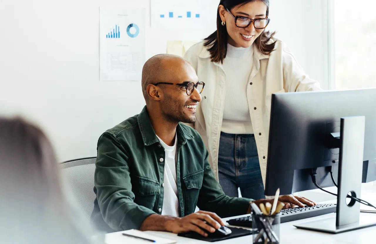 Man and woman in an office space working together on a computer