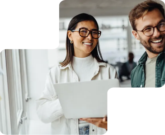 Woman and man smiling in a workplace and holding a computer