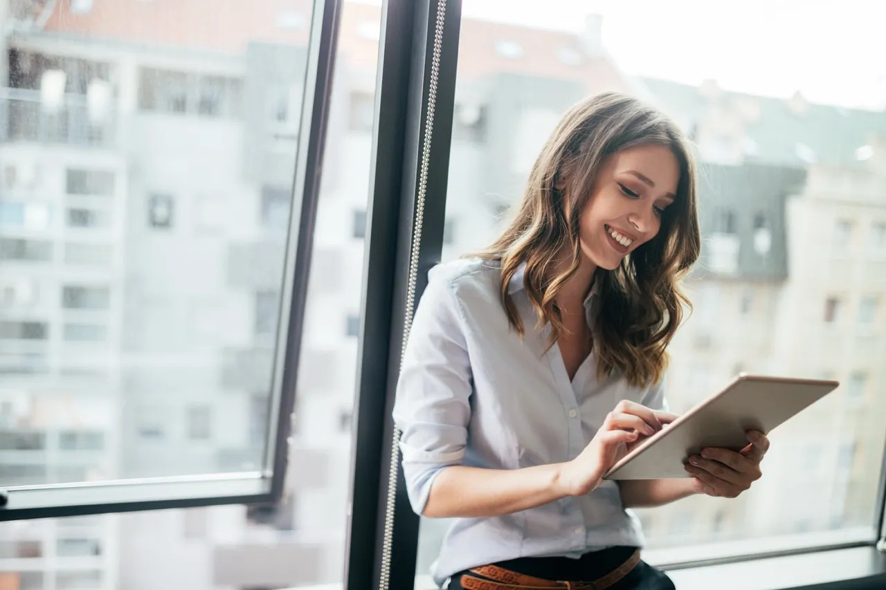 Woman in work attire smiling at tablet
