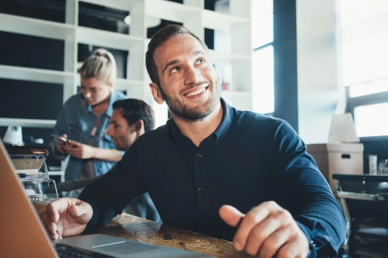 Man smiling looking up at a coworker in an office setting