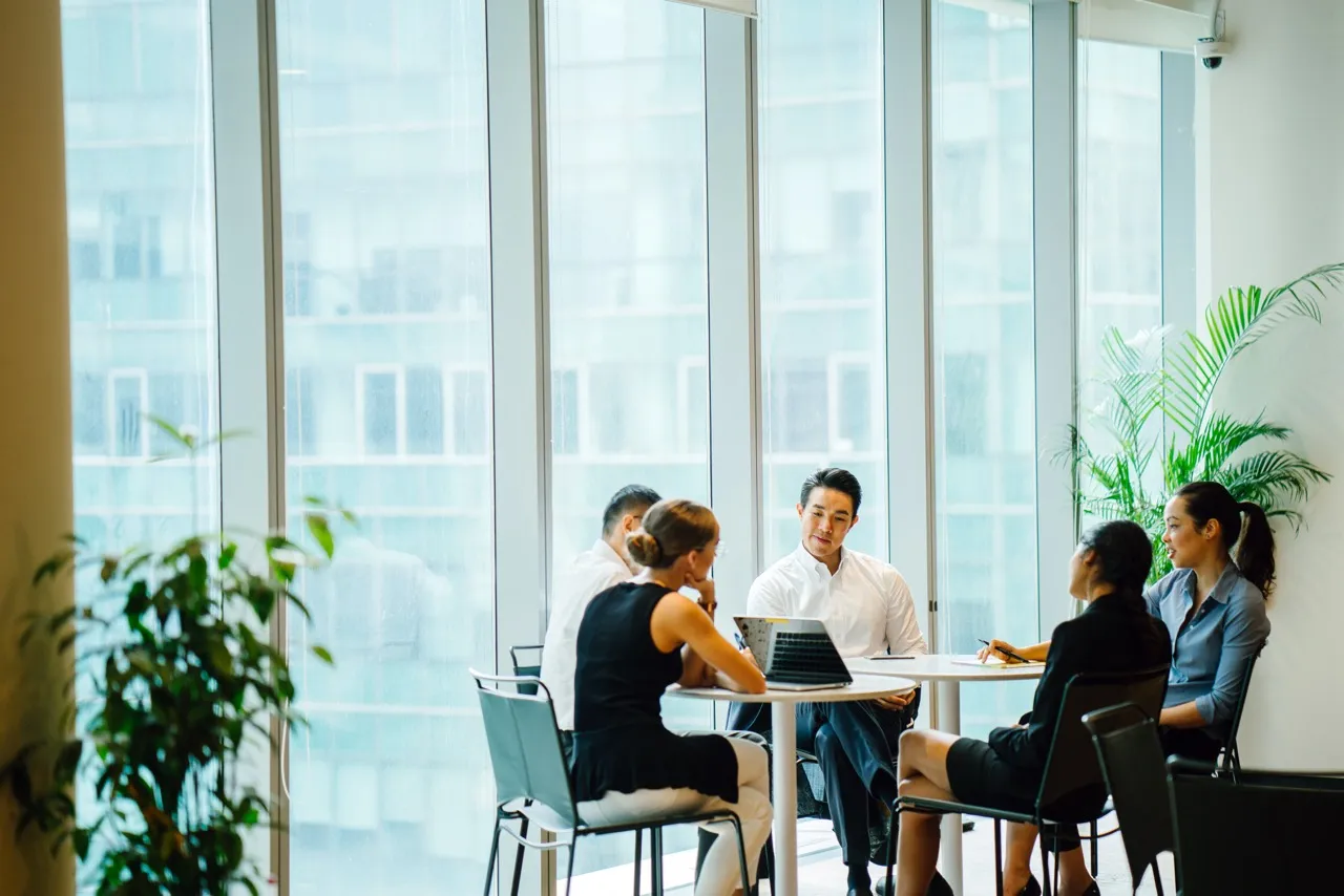 group meeting in a large meeting room with tall floor-to-ceiling windows 