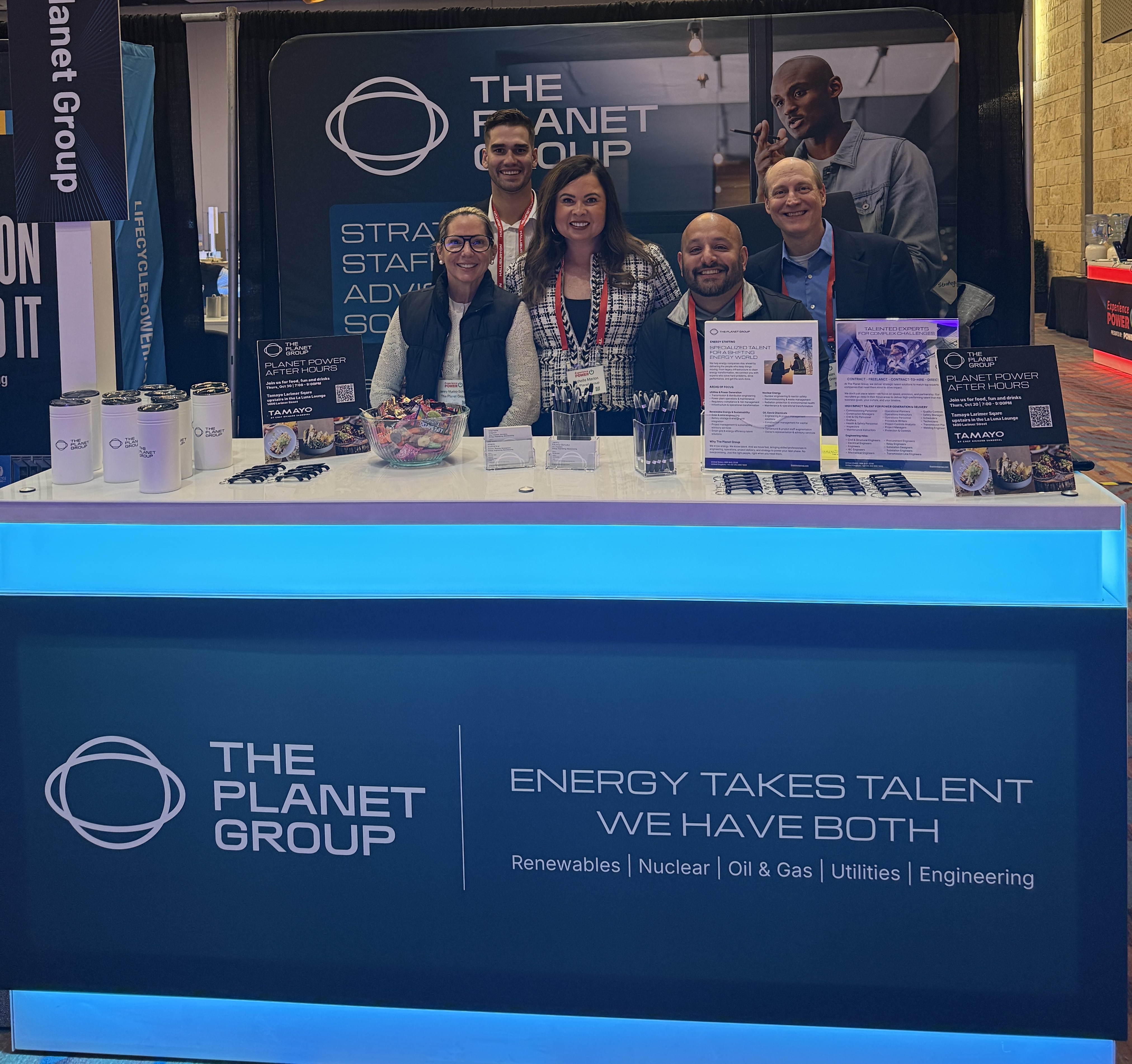 The Planet Group team's smiling faces at their booth on the expo floor at Experience Power 2025