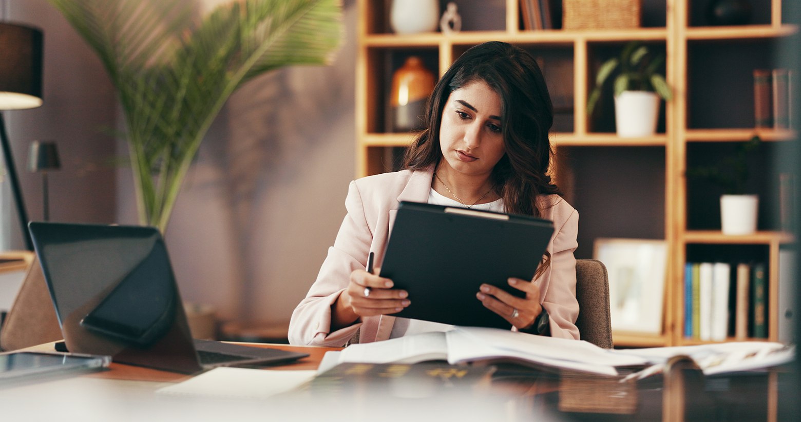 Executive woman reviewing documents on a tablet at her desk