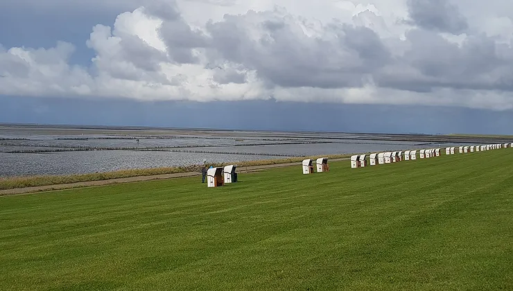 Der Deich und die Nordsee mit mehreren Strandkörben