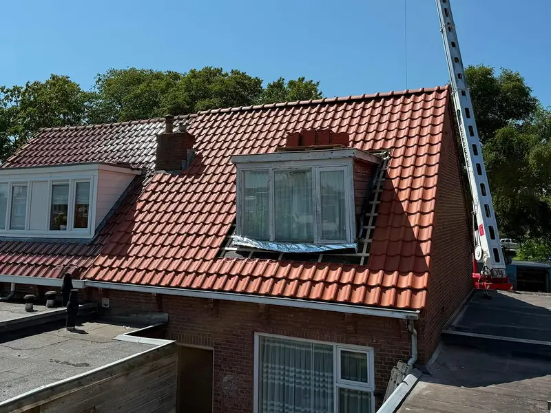 Nieuw pannendak op een rijwoning met dakkapel in Sneek, met de hoogwerker nog naast het huis