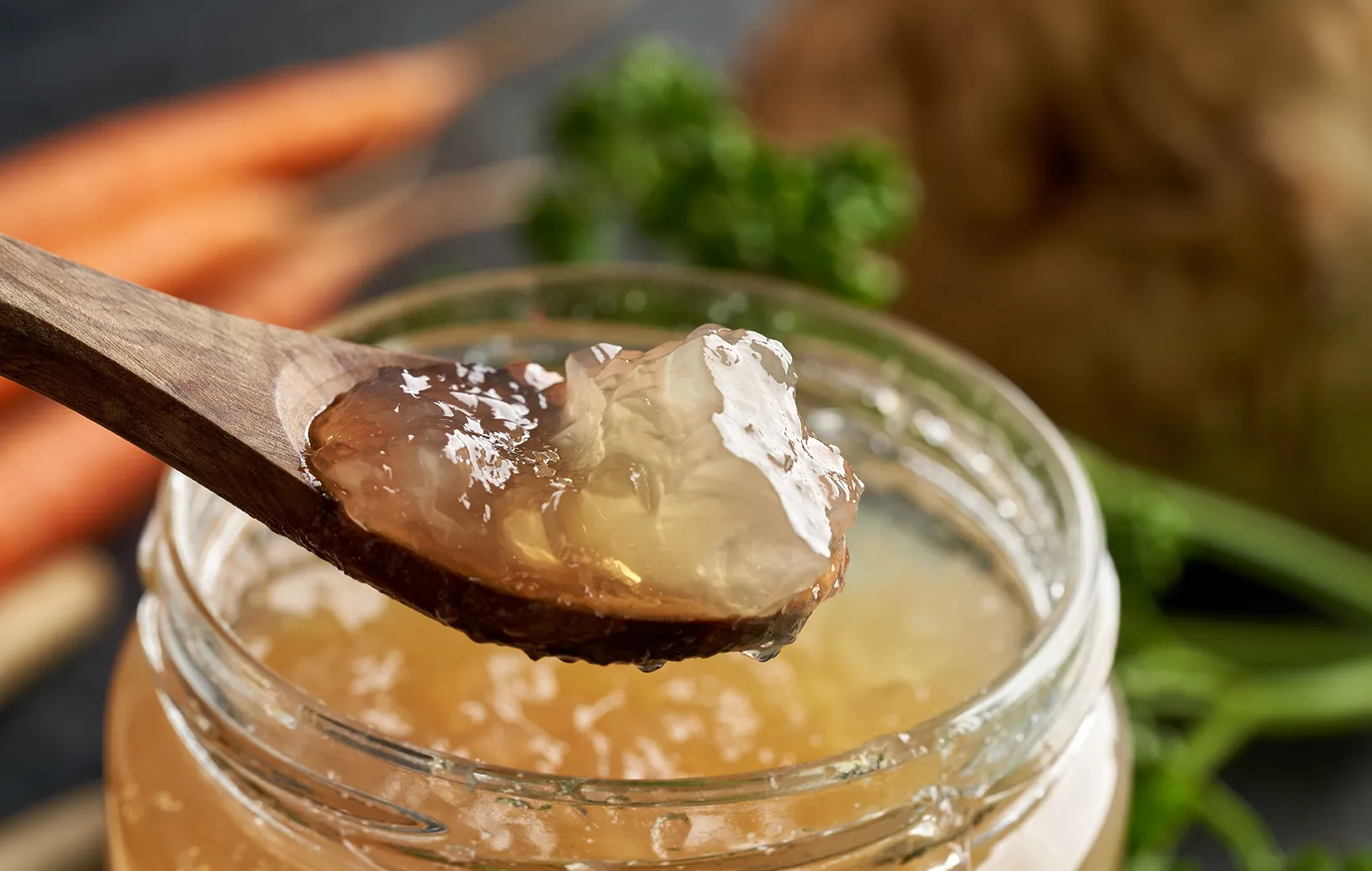 wooden spoon with gelatinous bone broth over a jar of broth