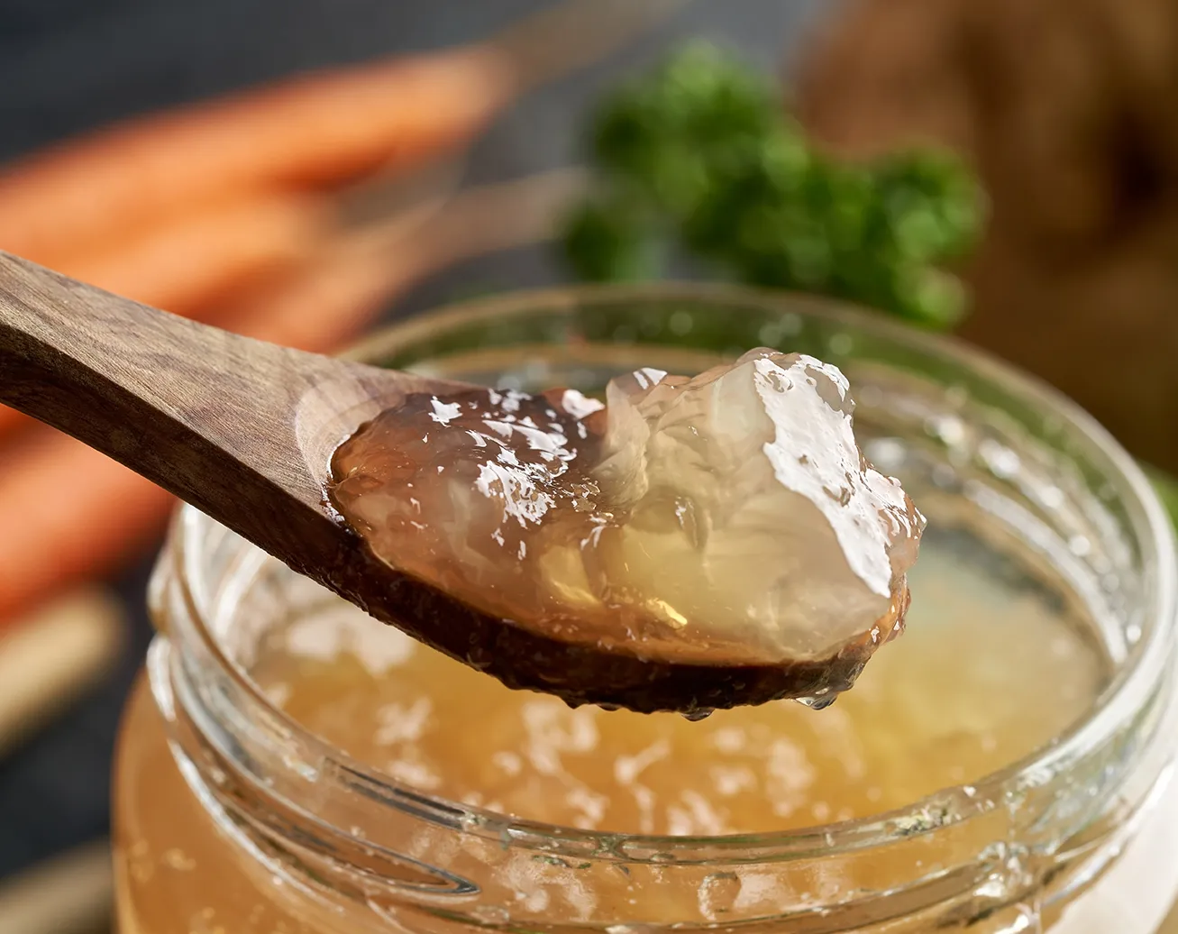 wooden spoon with gelatinous bone broth over a jar of broth