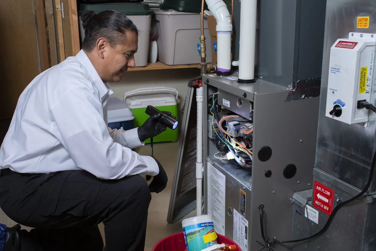 Technician inspects furnace with flashlight.