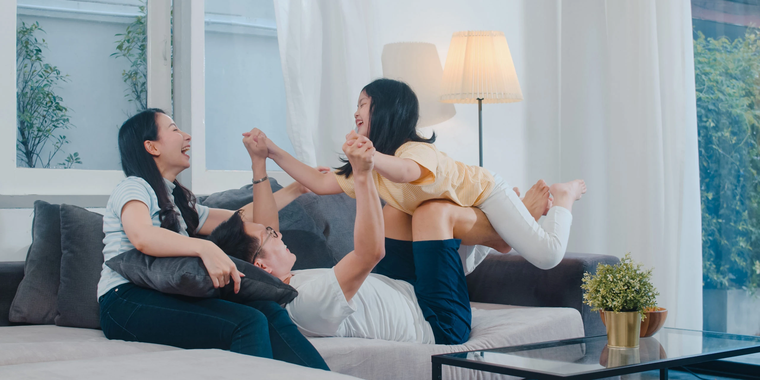 Happy family plays on living room couch.