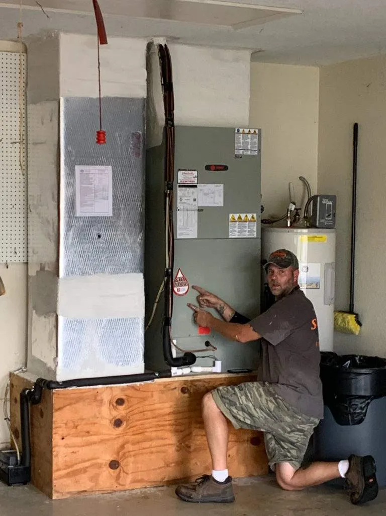 Technician inspecting HVAC system and water heater in utility room
