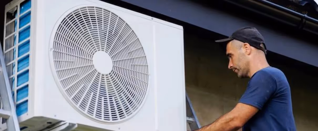 Technician installing or repairing a large white air conditioning unit outside