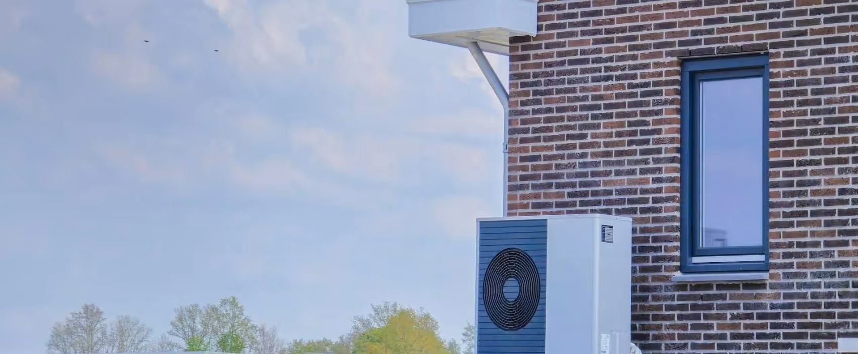 Blue and white heat pump installed on brick building exterior
