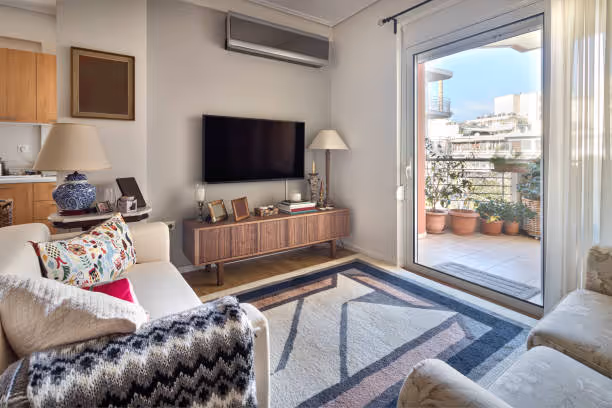 Cozy living room with TV, modern furniture, and balcony with potted plants
