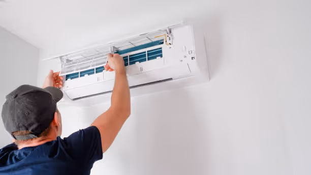 Technician installing or adjusting wall-mounted air conditioning unit