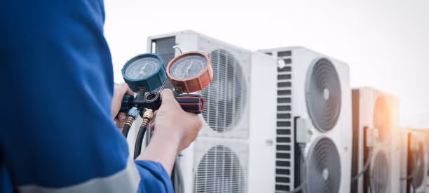 Technician checking air conditioning unit with pressure gauges