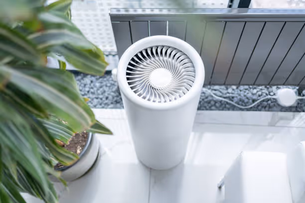 White cylindrical air purifier with turbine design near potted plant