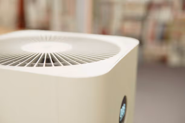 White air purifier with circular vent on top in blurred room setting