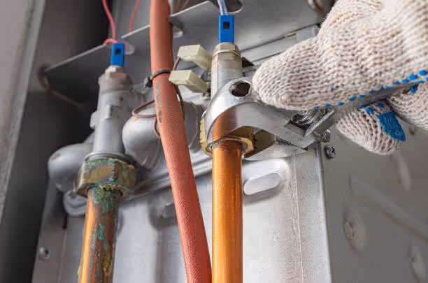 Gloved hand adjusting plumbing pipes with wrench in mechanical system