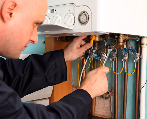 Technician repairing electrical connections inside a heating system