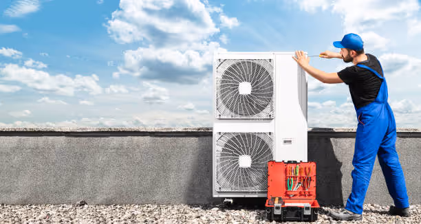 Technician in blue uniform working on an air conditioning unit outdoors