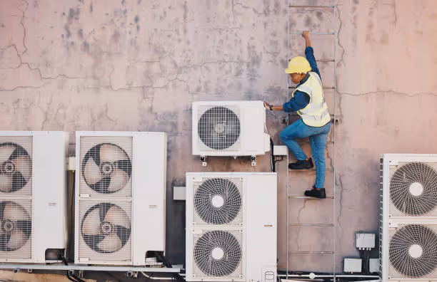 Worker in safety gear climbing ladder to inspect air conditioning units