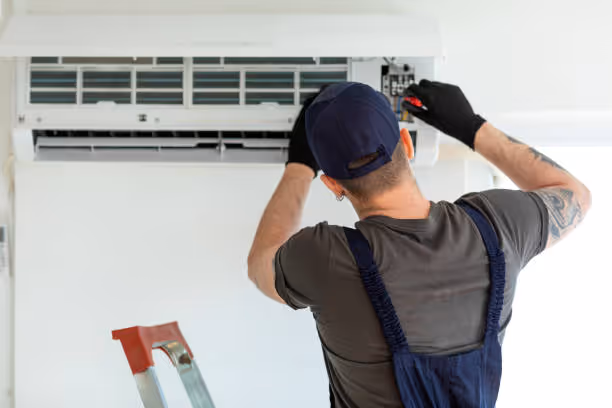 Technician installing or repairing air conditioning unit on wall