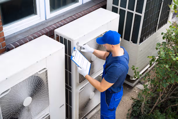 Technician in blue uniform checking outdoor air conditioning unit