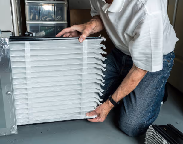 Person checking and handling a large white air filter or vent