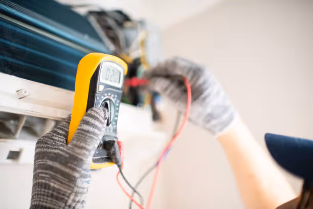 Technician using multimeter to check electrical connections in HVAC system