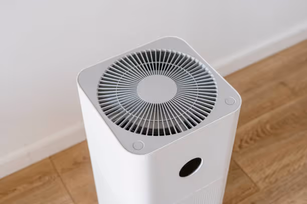 White square air purifier with circular ventilation grid on wooden floor