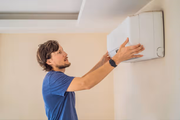 Man installing white air conditioning unit or electric heater on wall