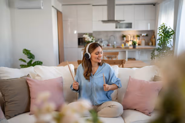 Woman enjoying music with headphones while sitting on cozy sofa at home